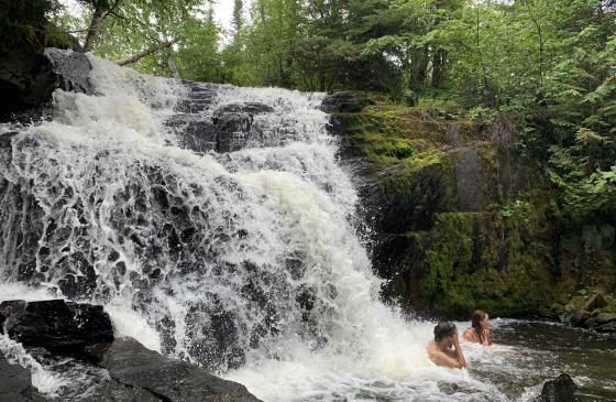 Photo of 2 people swimming in a waterfall