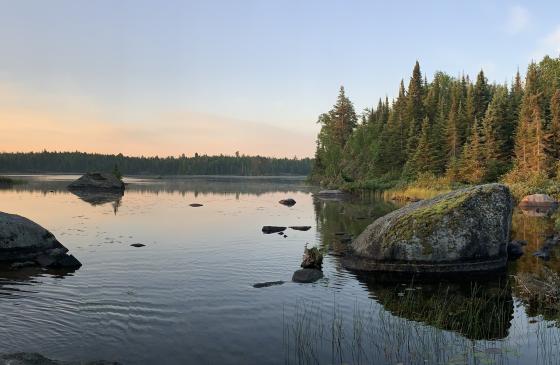 Photo of glassy water with Boundary Waters sun rise over it