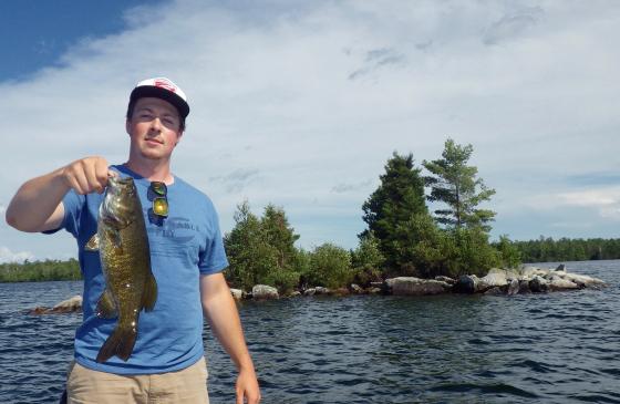 Photo of man wearing a ballcap holding up a fish with one hand