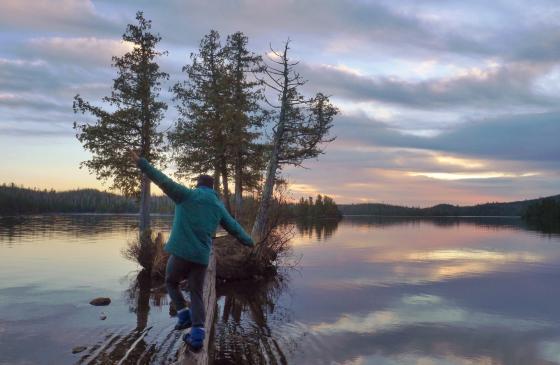 Photo of person walking on a log towards an island in the Boundary Waters