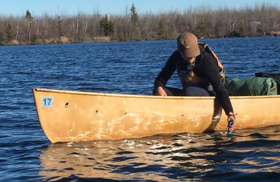 Amy Freeman reaching over side of canoe to accept water quality sample