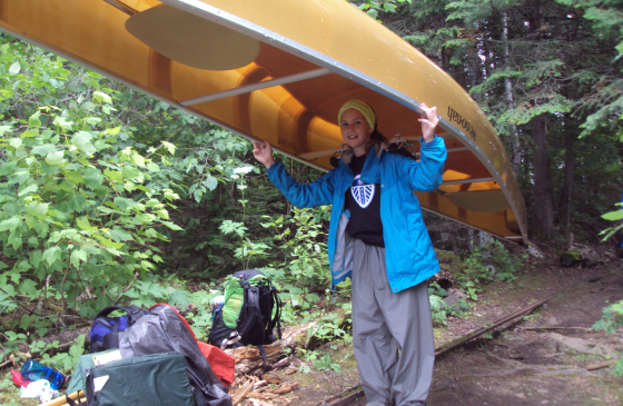 Photo of Grace Christenson portaging a canoe