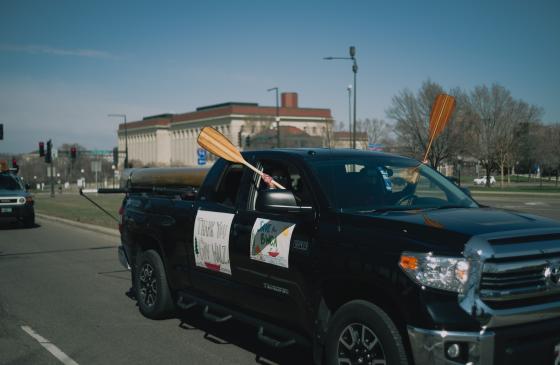 Image of truck driving by with people holding canoe paddles out windows