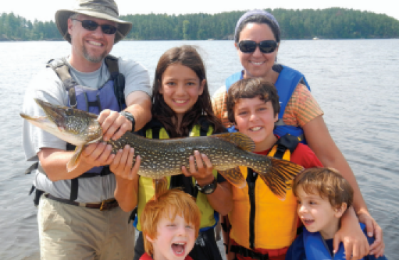 6 people standing next to a lake holding a big fish 