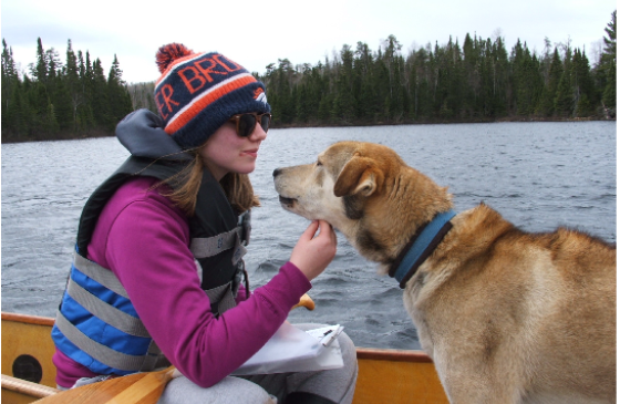 Photo of woman face to face with a sled dog in a canoe