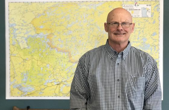 Photo of Executive Director Tom Landwehr standing infront of yellow map