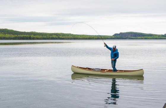 photo of man standing up fishing in a Merrimack Canoe