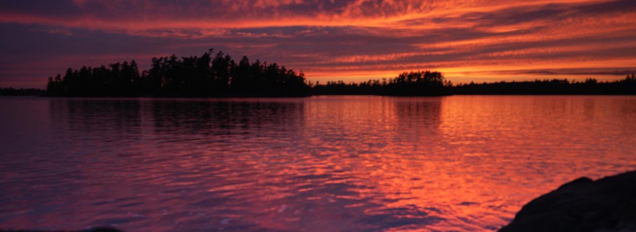 Deep orange and purple sunset with islands silhouetted out on the water