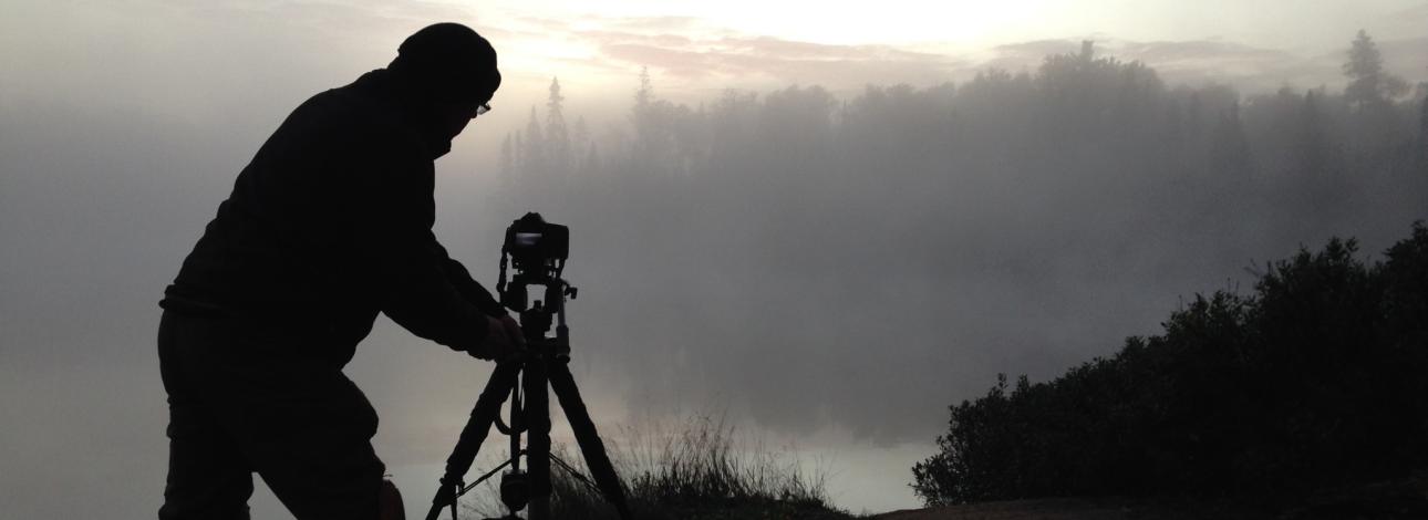Person with camera on misty lake 