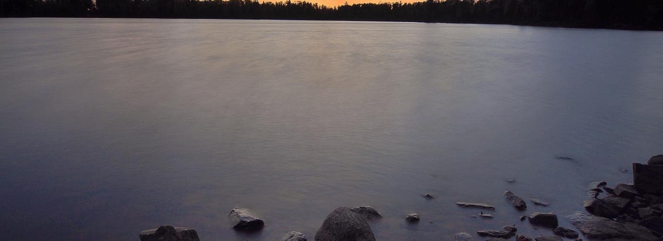 Boundary Waters Lake at sunset along shoreline 